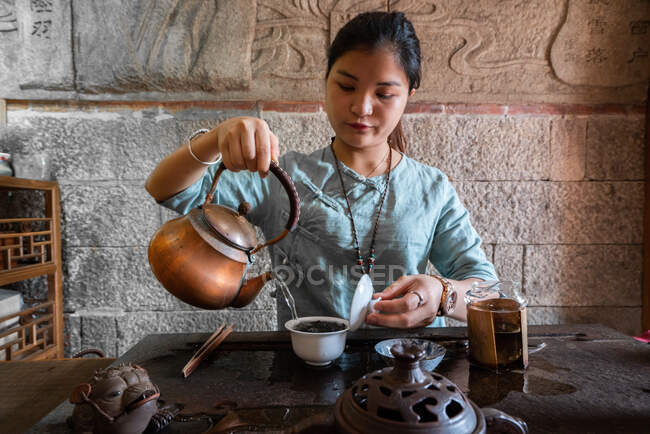 Junge Asiatin gießt Wasser aus Kanne und kocht Tee bei traditioneller Zeremonie — Stockfoto
