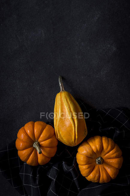 Halloween decoration of pumpkins on napkin on dark background with copy space. — Stock Photo