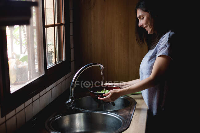 Mujer lavando ensalada en fregadero - foto de stock