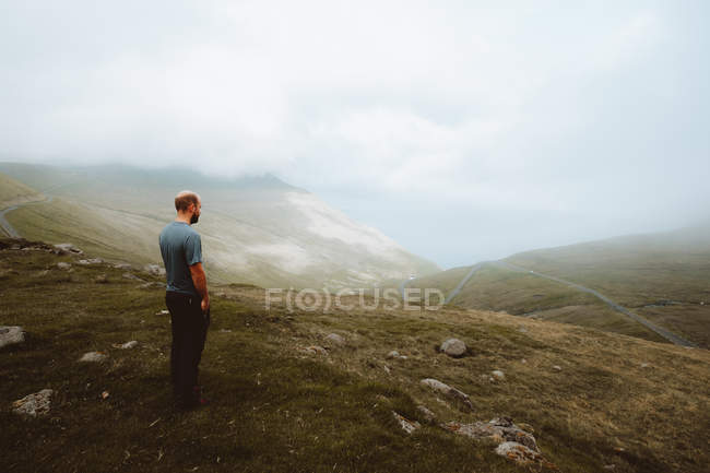 Männlicher Wanderer steht an der Küste und blickt auf das Meer auf der Insel Feroe — Stockfoto