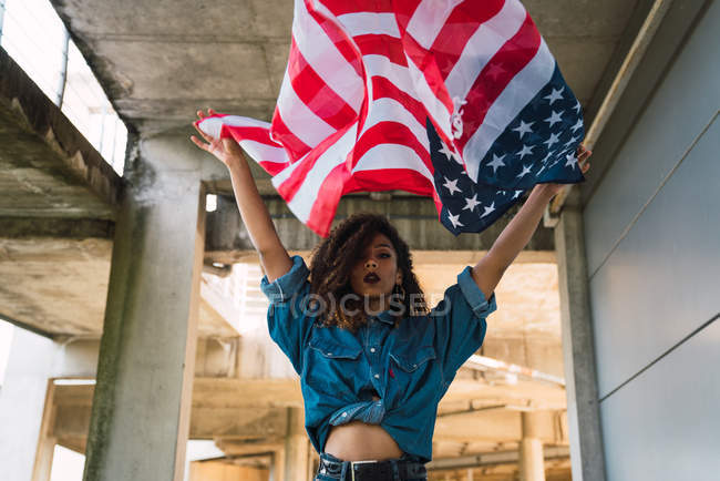 Молода жінка в джинсового одягу тримає прапор Америки — стокове фото