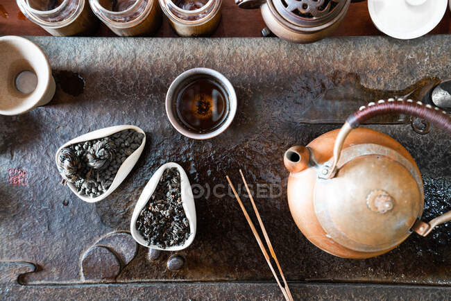 De arriba la tetera y las hojas secas de té sobre la mesa oriental para la ceremonia tradicional - foto de stock