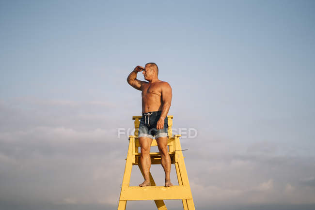Strong man rescuer keeps watch on beach — Stock Photo