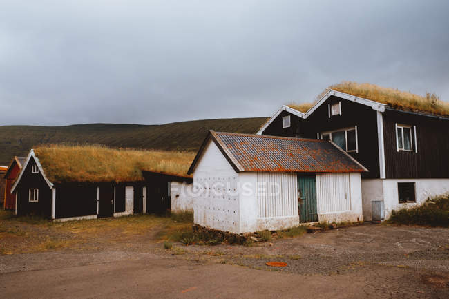 Casas rurales grungy marrón con hierba seca en los techos de las Islas Feroe - foto de stock