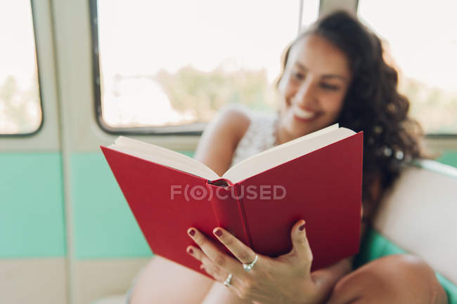 Gros plan de la femme assise à l'intérieur de la caravane et livre de lecture — Photo de stock