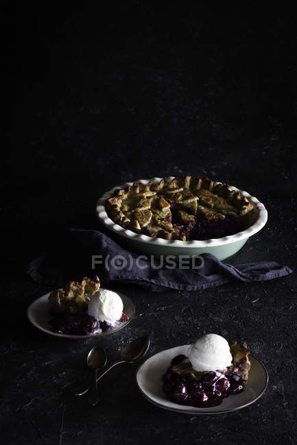 Fresh baked tasty berry pie served with ice cream on dark background — Stock Photo