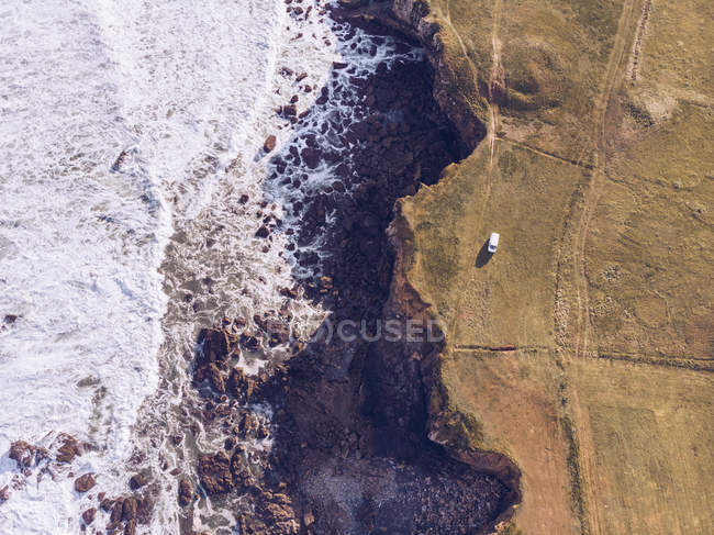 Herrlicher Drohnenblick auf drei Fahrzeuge, die auf einer Klippe in der Nähe des plätschernden Meeres in Asturien, Spanien, stehen — Stockfoto
