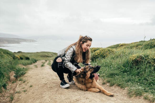 Mujer joven acariciando perro en la naturaleza - foto de stock