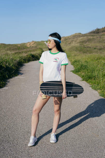Stylish teen girl with long board in summertime — Stock Photo