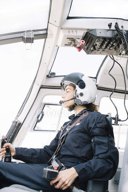 Pilote féminin concentré assis et opérant en hélicoptère — Photo de stock