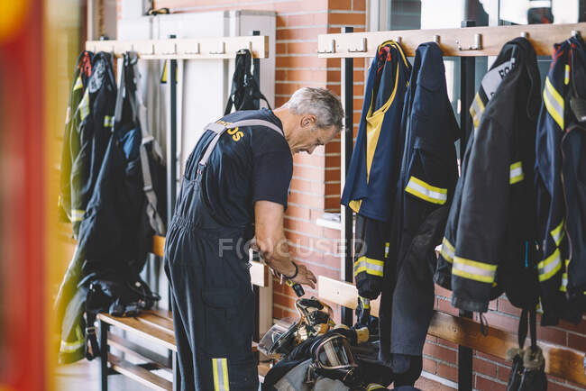 Bomberos vistiéndose en estación de bomberos. - foto de stock