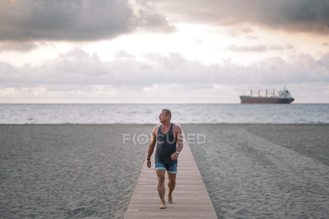Vieil homme fort posant sur la plage — Photo de stock
