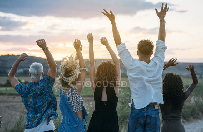 Gruppe junger Leute in lässigen Outfits lachen und tanzen, während sie gemeinsam Spaß in der schönen Landschaft haben — Stockfoto
