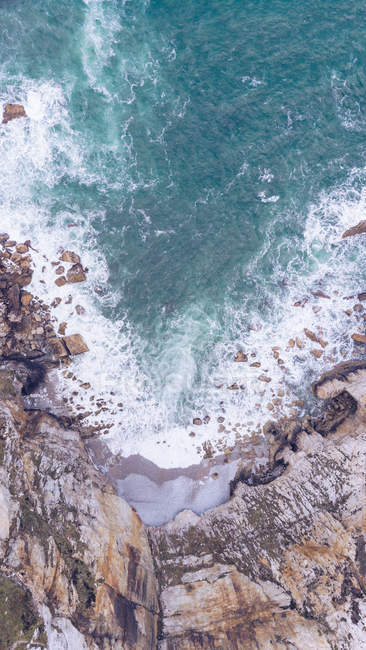 Amazing view of sea water splashing near long rocky cliff on cloudy day in Asturias, Spain — Stock Photo
