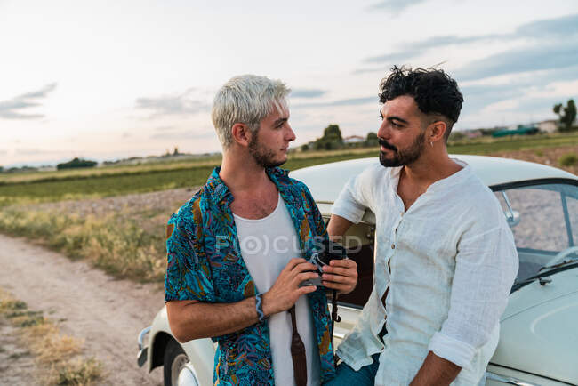 Men chatting with retro camera and vintage car — Stock Photo