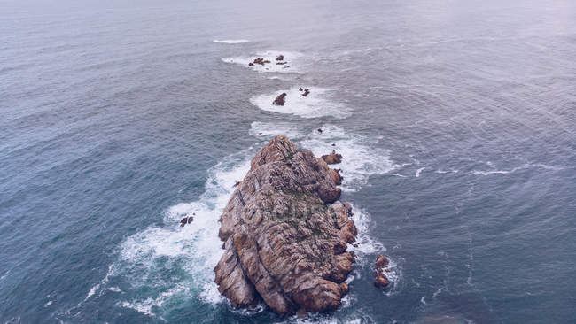 Химерний безпілотний вид на морську воду, що бризкає по малій скелі в Астурії (Іспанія). — стокове фото