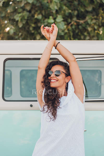 Allegro bruna donna in occhiali da sole in posa vicino van — Foto stock