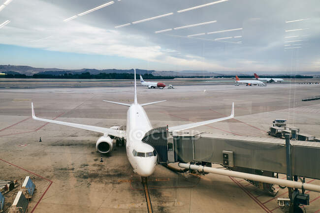 De cima vista de avião branco estacionado no chão de aterrissagem com o dedo fixo à entrada no fundo do céu nublado — Fotografia de Stock