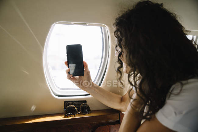 Donna che scatta foto attraverso la finestra dell'aeroplano — Foto stock