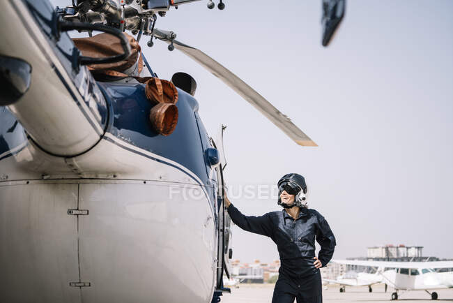 Piloto niña posa con su helicóptero y casco - foto de stock
