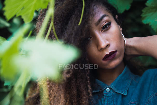 African American woman standing in green leaves — Stock Photo