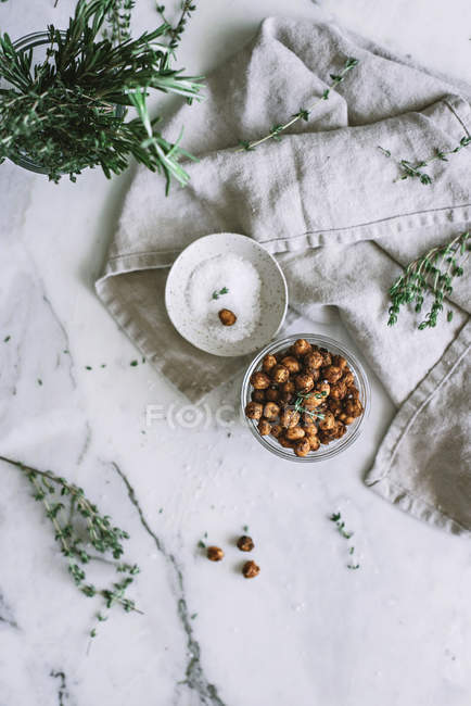 Roasted chickpeas in glass bowl on white marble surface — Stock Photo