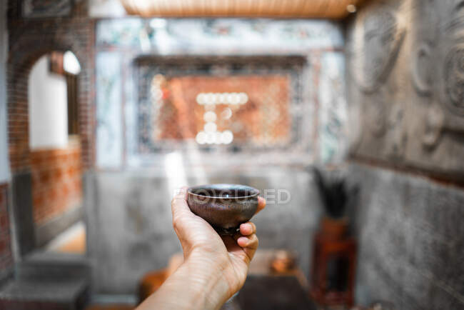 Cosecha mano de persona irreconocible sosteniendo taza de té oriental tradicional - foto de stock