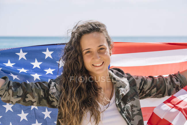 Una chica posando en la playa con la bandera de EE.UU.. - foto de stock