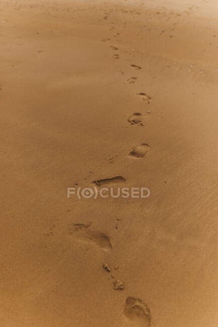 Цепочка человеческих следов, ведущих вперед по сухой песчаной поверхности — стоковое фото