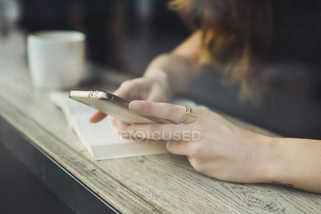 Крупный план женщины, использующей смартфон в кафе за стеклом — стоковое фото
