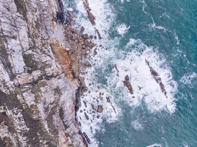 Дивовижний вид на морську воду, що бризкала біля стрімких скель у похмурий день в Астурії (Іспанія). — стокове фото