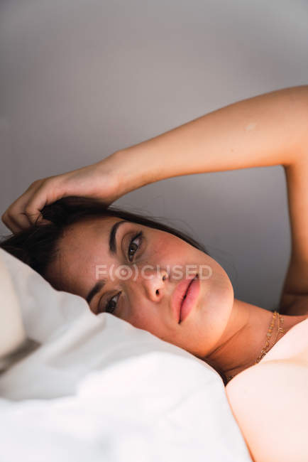 Portrait of young brunette woman lying in bed — Stock Photo