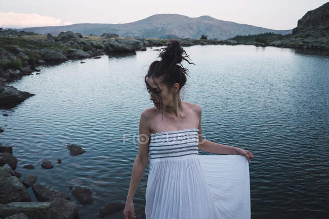 Junge elegante Frau im Kleid steht am plätschernden See — Stockfoto