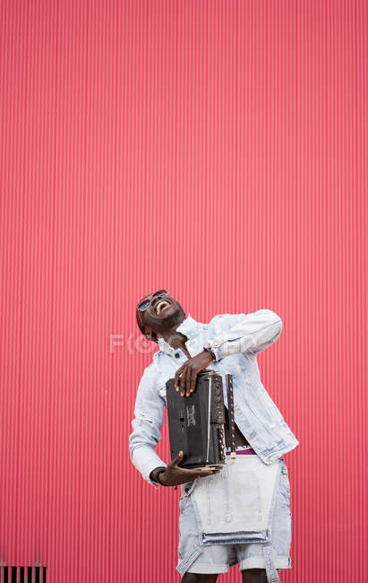 Homme afro-américain debout avec dispositif de radio vintage sur fond rouge — Photo de stock