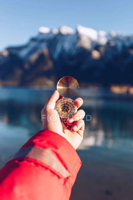 Mensch in roter Jacke mit goldenem Kompass an einem sonnigen Tag vor verschwommenem Hintergrund der kanadischen Berge — Stockfoto