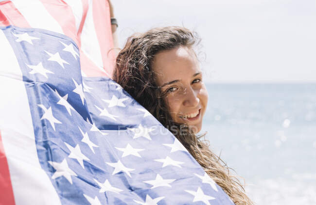 Una chica posando en la playa con la bandera de EE.UU.. - foto de stock