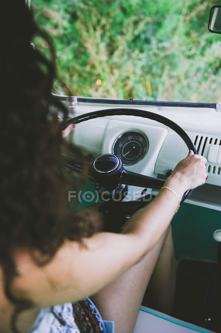 Donna irriconoscibile seduta sul sedile del conducente di auto d'epoca e guida nella natura — Foto stock