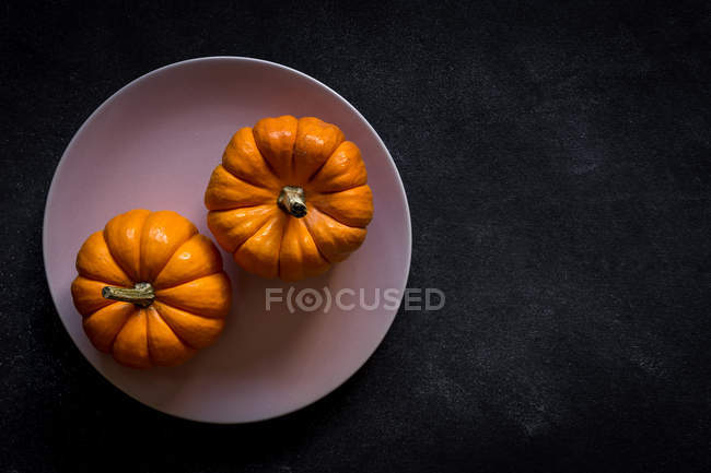 Decorazione di Halloween di zucche su piatto su sfondo scuro con spazio di copia . — Foto stock