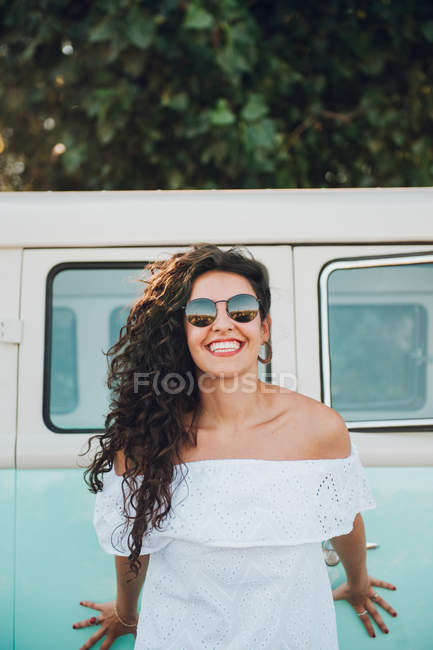 Mulher morena alegre em óculos de sol posando na frente da van — Fotografia de Stock