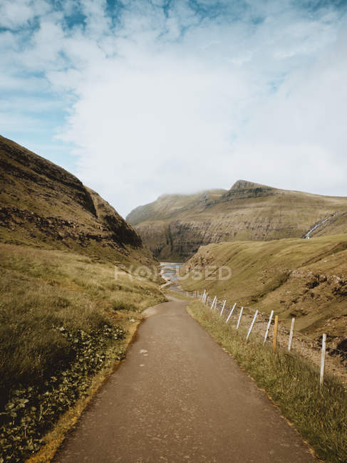 Veduta panoramica del piccolo sentiero verso il lago tra le colline delle Isole Feroe — Foto stock