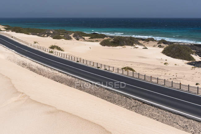 Estrada através do deserto e água do oceano nas ilhas Canárias — Fotografia de Stock