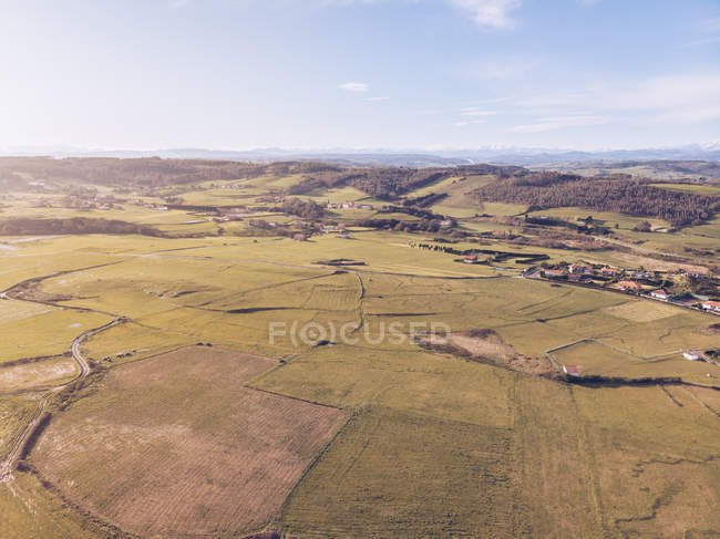 Hermosa vista del dron de los campos de cultivo verde y pequeño asentamiento en el día soleado en Asturias, España - foto de stock