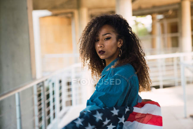 Jovem mulher de camisa jeans segurando bandeira da América — Fotografia de Stock