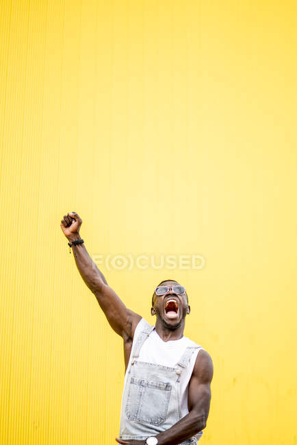 Hombre feliz funky en gloria con el puño apretado sobre fondo amarillo - foto de stock