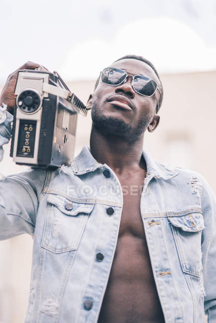 Черный человек в солнечных очках ходит с винтажным радиоприбором — стоковое фото