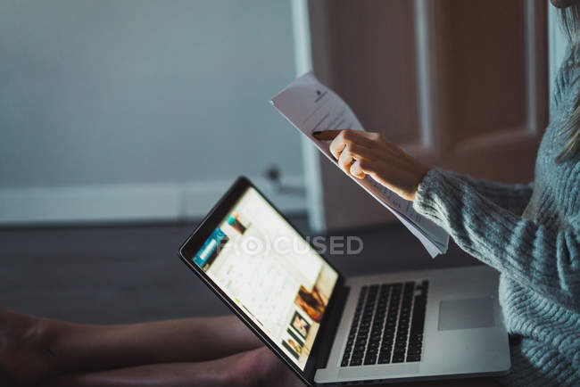 Close-up of female hands holding papers at laptop — Stock Photo