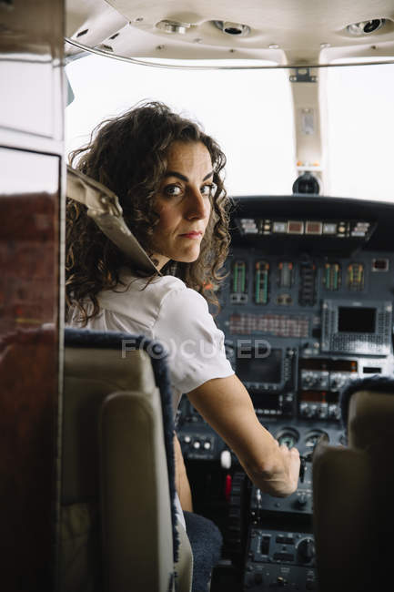 Brünette Frau navigiert Flugzeug und schaut in Kamera — Stockfoto