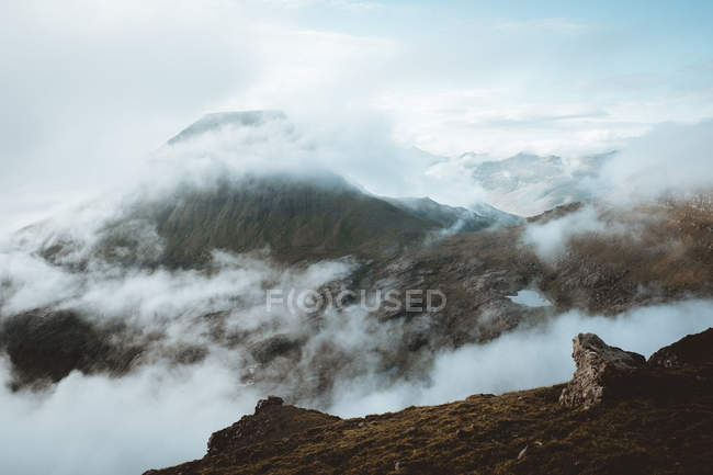 Montañas rocosas en las nubes en las Islas Feroe - foto de stock