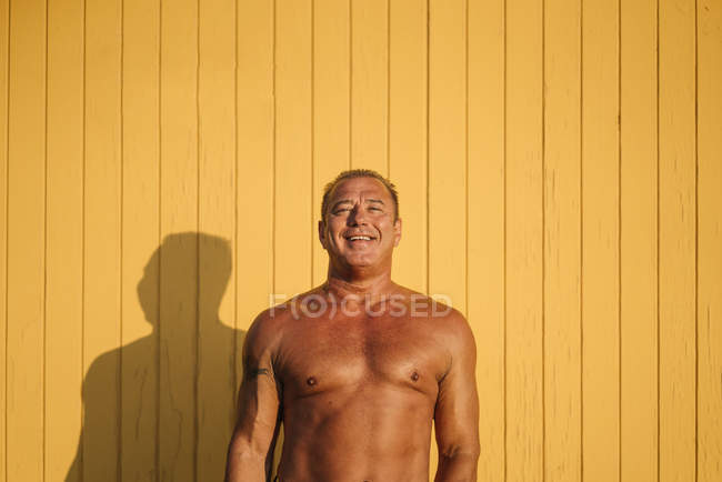 Muscular older man poses yellow background — Stock Photo