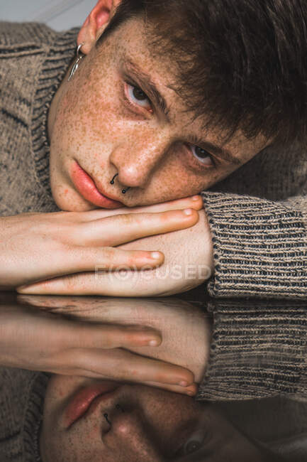 Homem sardento de camisola deitado a mãos — Fotografia de Stock